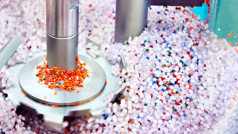 Maquinaria industrial procesando pellets plásticos reciclados mediante tecnologías de valorización de residuos.